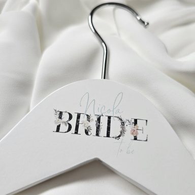 Bridal Hangers White hanger with "Bride" printed in elegant script, resting on soft fabric.