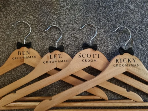 Grooms Hangers Wooden hangers with names printed and small black bows attached.